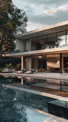 a house with a pool in front of it and trees around the pool area on either side