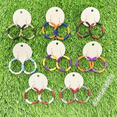 six pairs of earrings with different colors on them sitting in the green grass next to each other