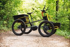 two bikes parked on the side of a dirt road in the woods with trees behind them