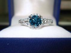 a blue and white diamond ring sitting on top of a display case in a box