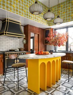 a kitchen with an island and yellow accents on the ceiling, along with two stools