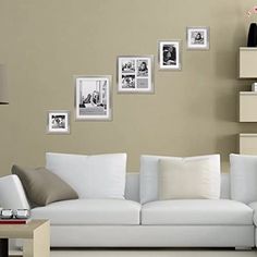 a living room with white furniture and pictures on the wall