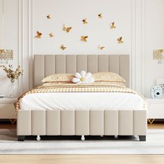 a white bed sitting next to a wall with gold butterflies on the headboard and foot board