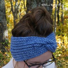 a woman wearing a blue headband in front of some trees and leaves with her eyes closed