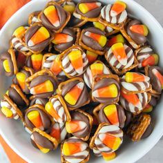 a white bowl filled with candy corn on top of a wooden table next to an orange towel