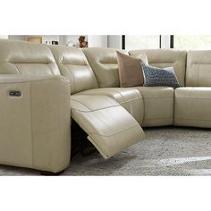 a beige leather sectional sofa with recliners and pillows