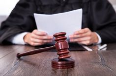 a judge holding a piece of paper next to a wooden gaven on top of a table