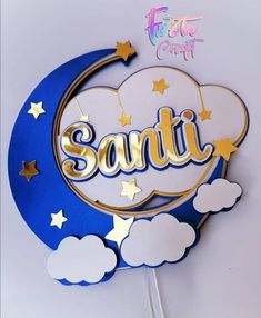 a cake topper with the word santa written on it in gold and silver foil