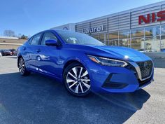 a blue car parked in front of a nissan dealership