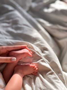 a woman laying on top of a bed next to a baby's feet and toes