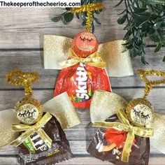 three candy bags with gold ribbon and two wrapped in foil, hanging from a christmas tree