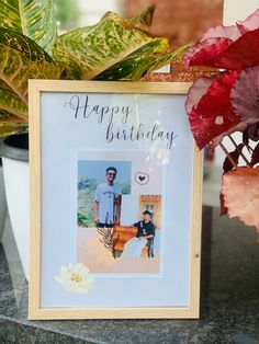 a happy birthday photo frame sitting next to a potted plant