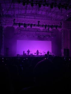 the stage is lit up with purple lighting and people are sitting in front of it