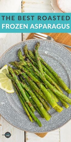 the best roasted frozen asparagus on a plate with lemon wedges and fork