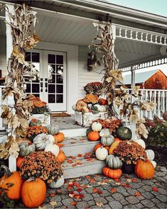 pumpkins and gourds are arranged on the porch