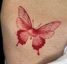 a red butterfly tattoo on the back of a woman's thigh