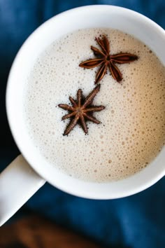 two star anisets sit on top of a cup of hot chocolate in a white mug