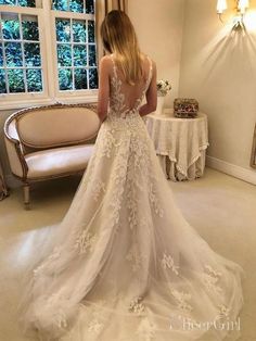 a woman in a wedding dress looking at herself in the mirror with her back to the camera