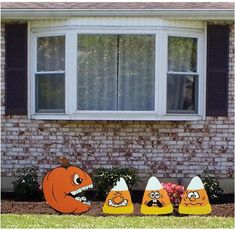 an assortment of halloween decorations in front of a brick house with windows and shutters