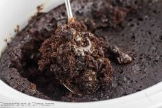 chocolate cake in a white bowl with a spoon sticking it into the batter and toppings