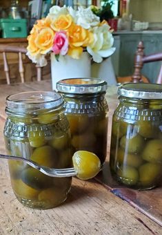 two jars filled with pickles sitting on top of a wooden table