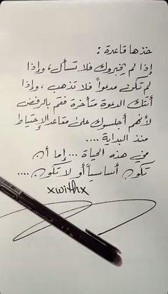 the writing is written in arabic and has an ink pen resting on top of it