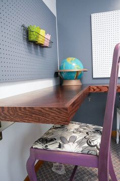 a purple chair sitting in front of a desk with a globe on top of it