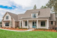 a house that is in the middle of a field with grass and trees around it