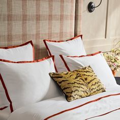 a bed with white and orange pillows on it's headboard next to a wall