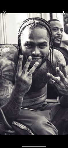 a black and white photo of a man with dreadlocks holding his hand up to his face