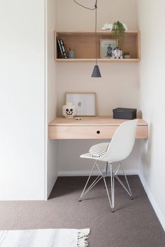 a white chair sitting in front of a desk with a lamp on top of it