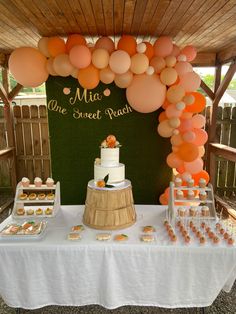 a table topped with lots of cake and desserts next to a sign that says mia one sweet peach