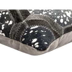 an animal print pillow on top of a white surface with black and white spots in the middle