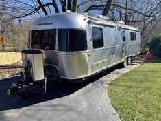 an rv parked on the side of a road next to a tree and grass area