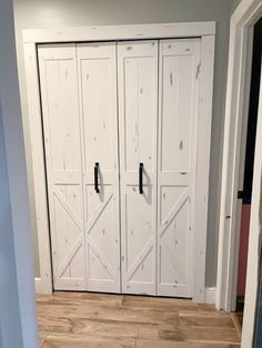 an empty room with white doors and wood flooring on the side of the wall