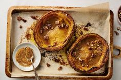 three baked desserts sitting on top of a baking tray next to a bowl of nuts