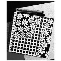 a black and white photo of a notebook with flower designs on it, next to a crayon marker