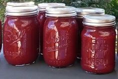 several jars filled with red liquid sitting on top of a table