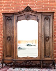 an old wooden armoire with a large mirror on it's front and side