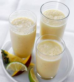 two glasses filled with white liquid next to sliced fruit