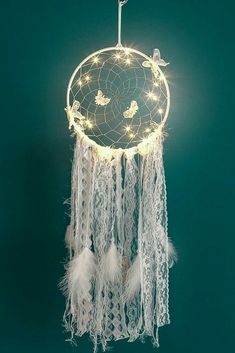 a white dream catcher hanging from the ceiling with lights on it's sides and birds flying around