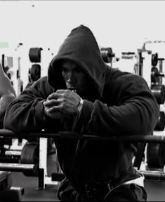 a man sitting in front of a barbell with his hands on his chest and looking at his phone