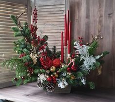 a christmas centerpiece with candles and greenery