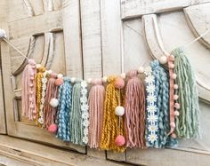 a string of tassels hanging from a wooden door with flowers and beads on it