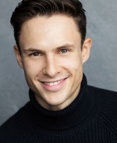 a smiling man in a black turtle neck sweater