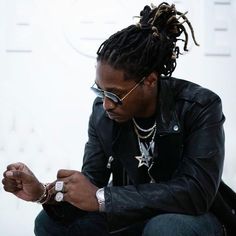 a man with dreadlocks sitting down and looking at his cell phone