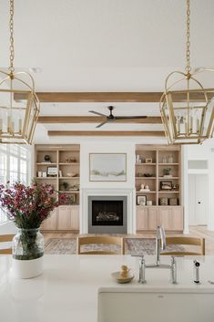 a large open kitchen with white counter tops and wooden beams on the ceiling, along with two hanging lights