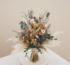 a vase filled with lots of different types of flowers on top of a white table