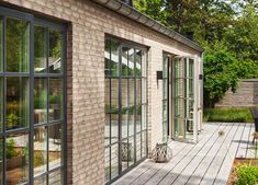 an outdoor patio area with wooden floors and brick walls, surrounded by greenery on both sides