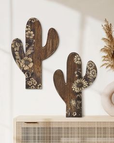 two wooden cactus sculptures sitting on top of a shelf next to a potted plant